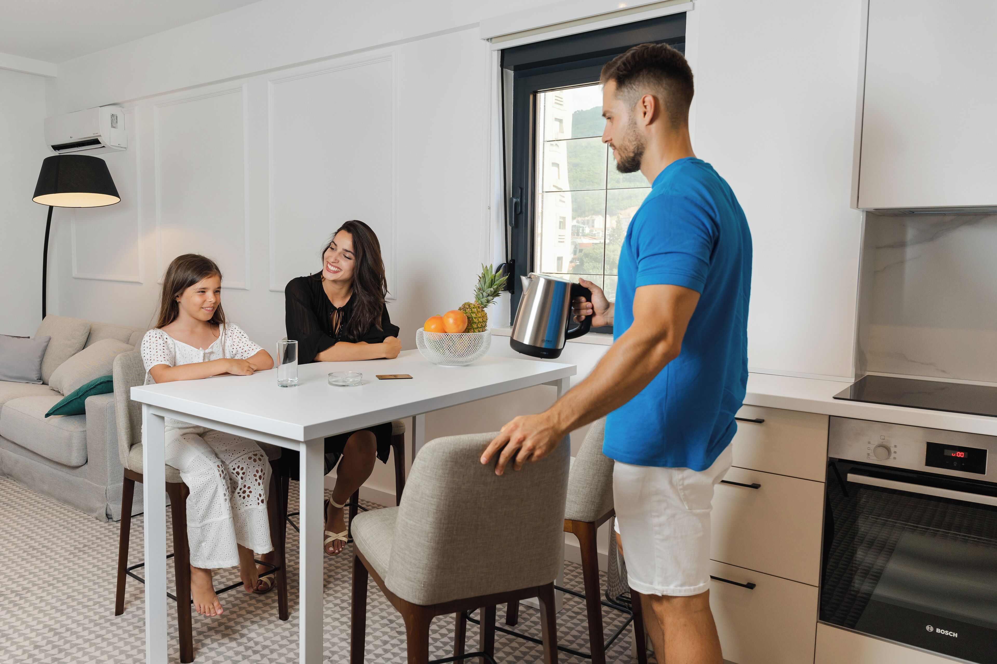 A modern kitchen with a Bosch oven, a dining table with chairs, and a window with a view of buildings.