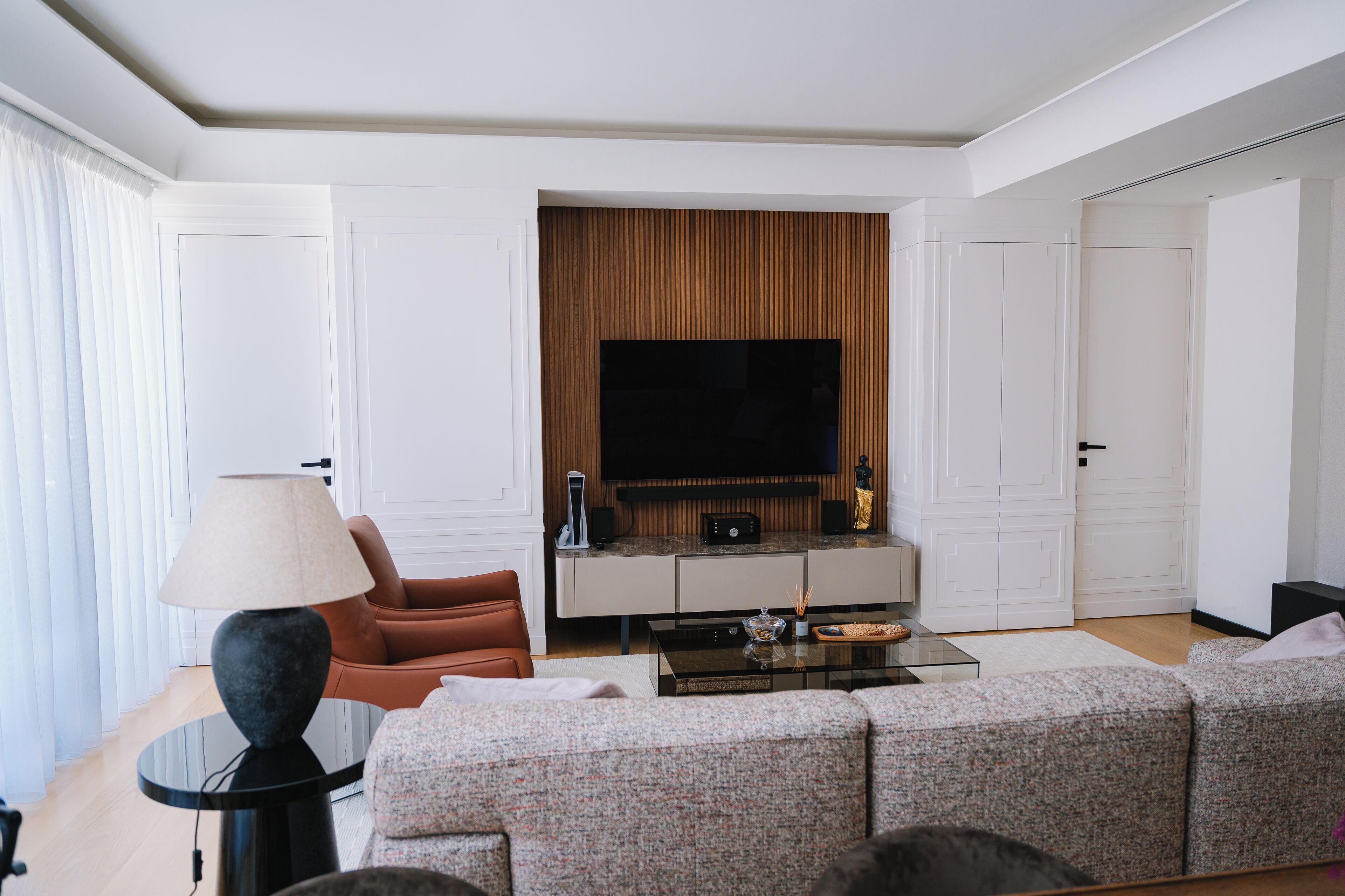 Una sala de estar moderna con sofá, mesa de centro, lámpara y televisión.