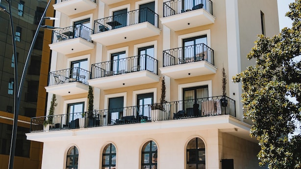 Un hotel de varios pisos con balcones, un área de café y un letrero.