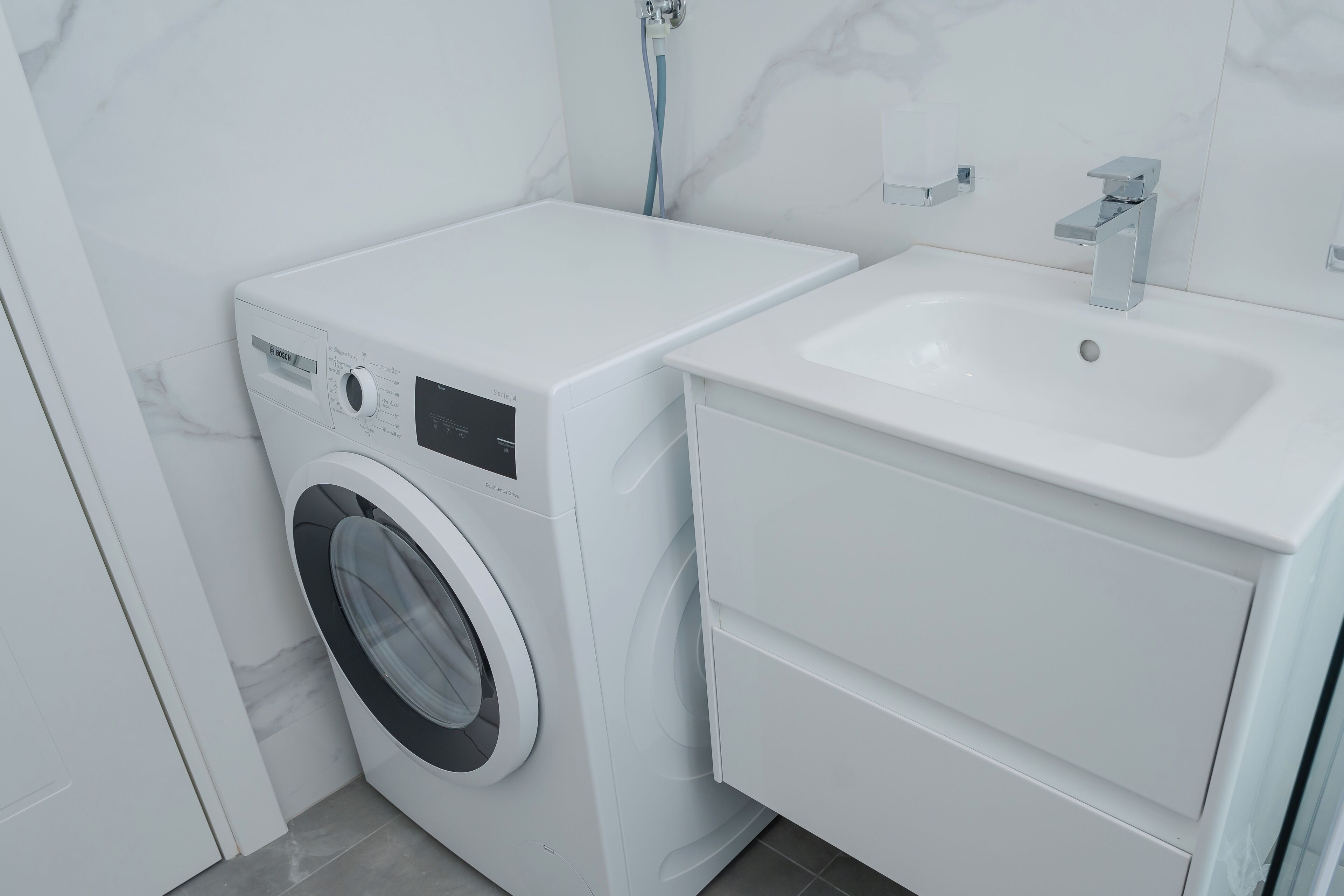 A compact, modern bathroom with a white washing machine and sink.