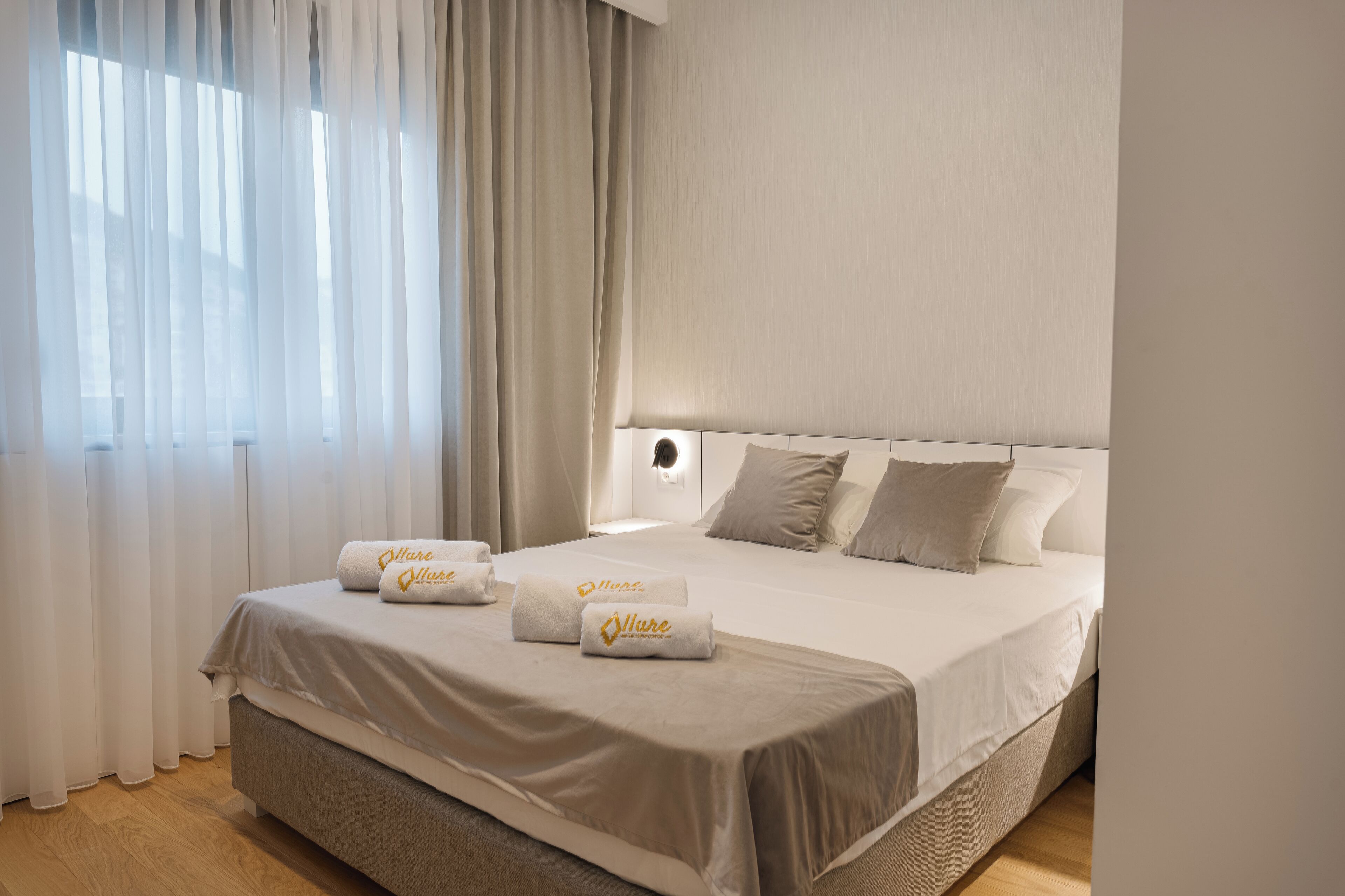 Camera d'albergo con un letto grande, due cuscini e due asciugamani con un logo.