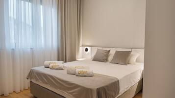 Camera d'albergo con un letto grande, due cuscini e due asciugamani con un logo.