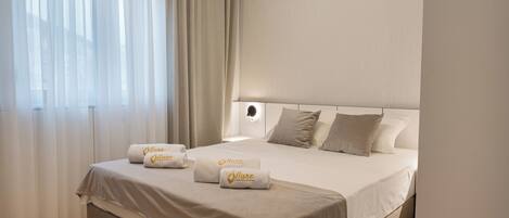 Habitación de hotel con una cama grande, dos almohadas y dos toallas con un logotipo.