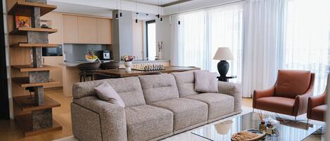 A modern living room with a sofa, a glass coffee table, and a red armchair.