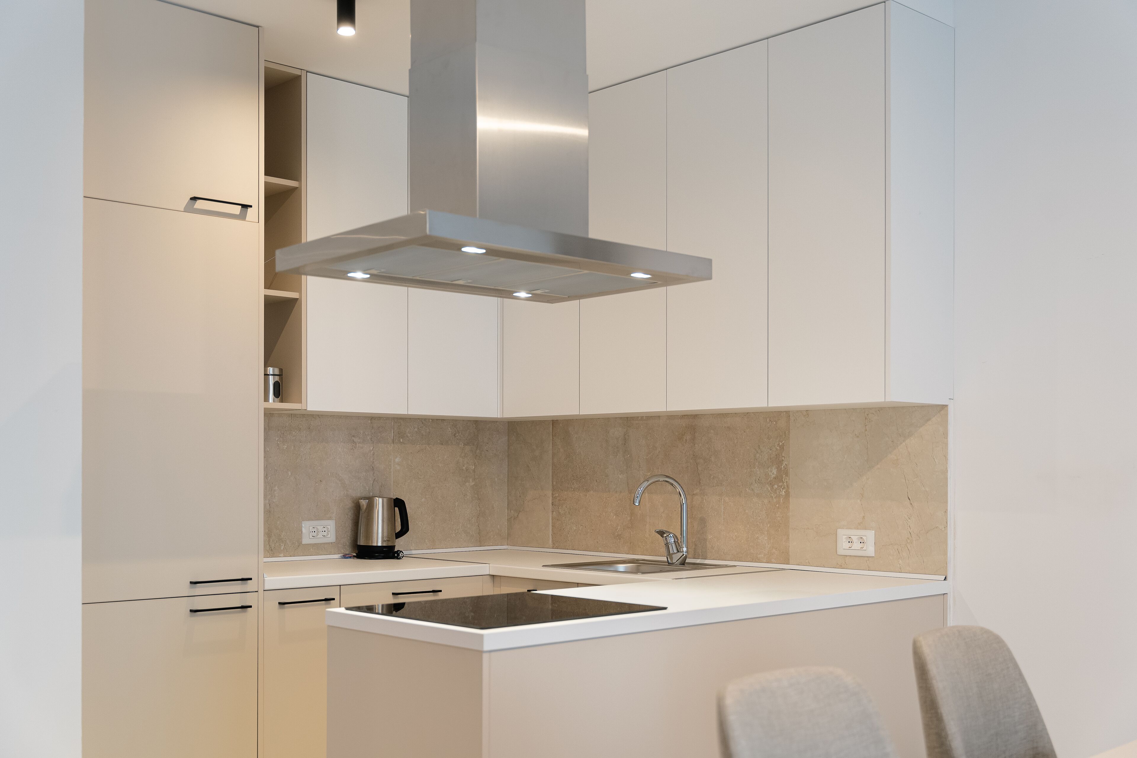 Una cocina moderna con una campana de acero inoxidable, un lavamanos doble y un horno empotrado.