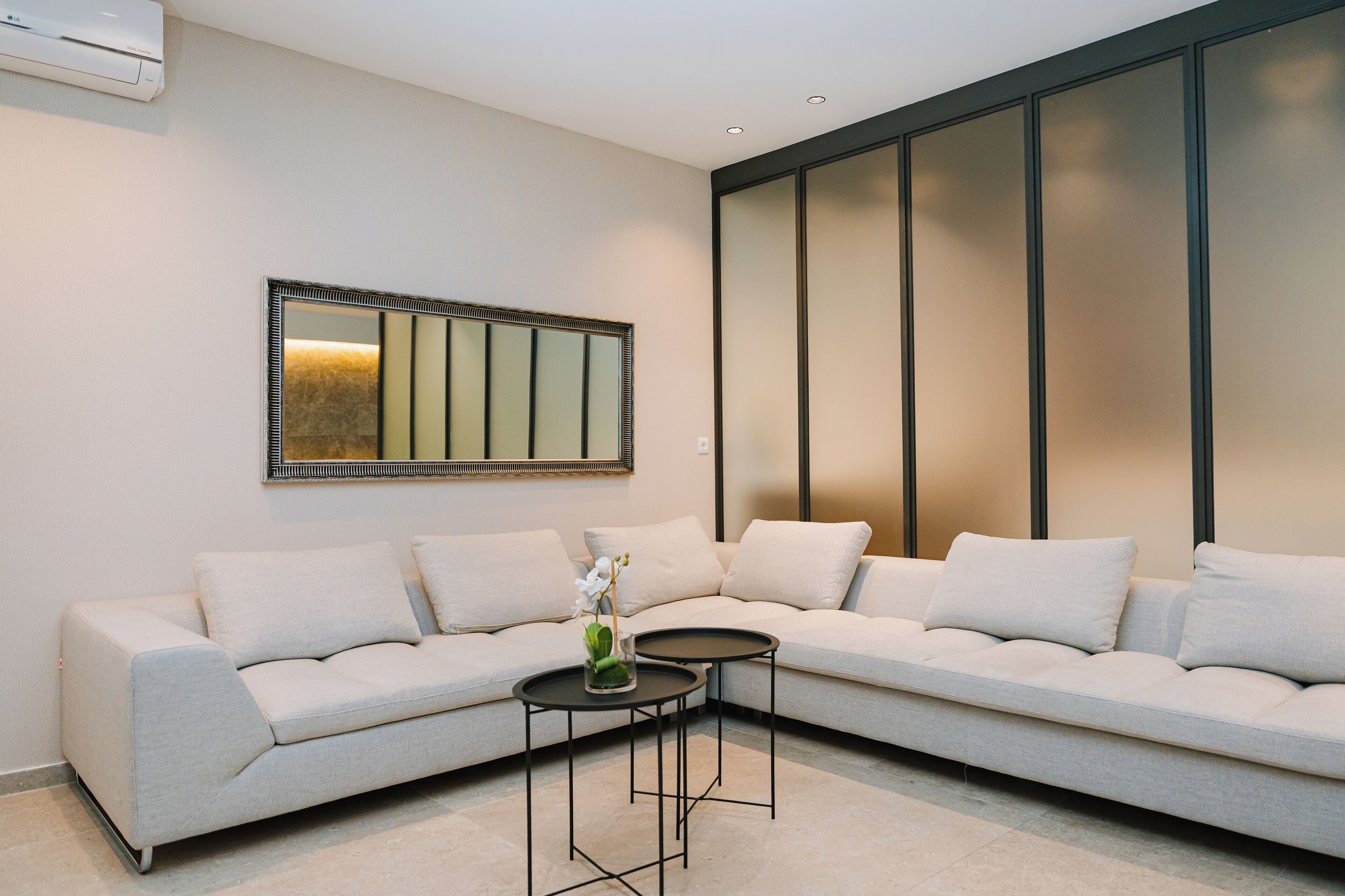Una sala moderna con un sofá modular, una mesita redonda y un espejo grande en la pared.