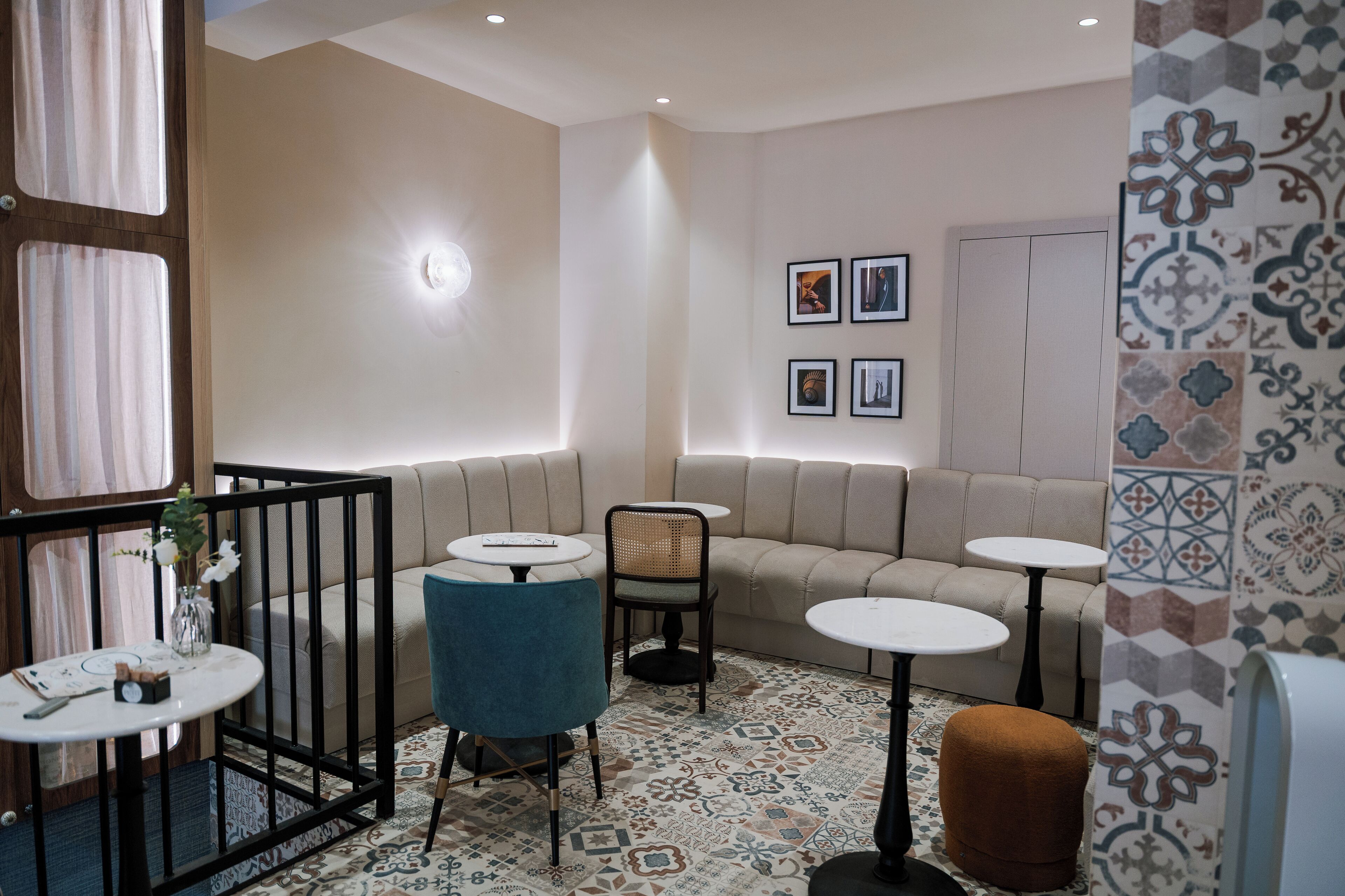 A modern lounge area with a sofa, two round tables, a chair, and a patterned floor.