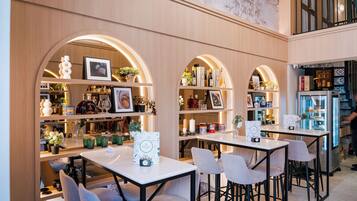 Un restaurante con varias mesas y sillas, estanterías con diversos objetos y un refrigerador de exhibición.