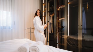 Una habitación de hotel con cama, vestidor y ventana con cortinas.