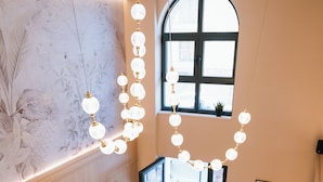 Un interior con una zona de estar, un amplio ventanal de arco y una pared con estampado floral.