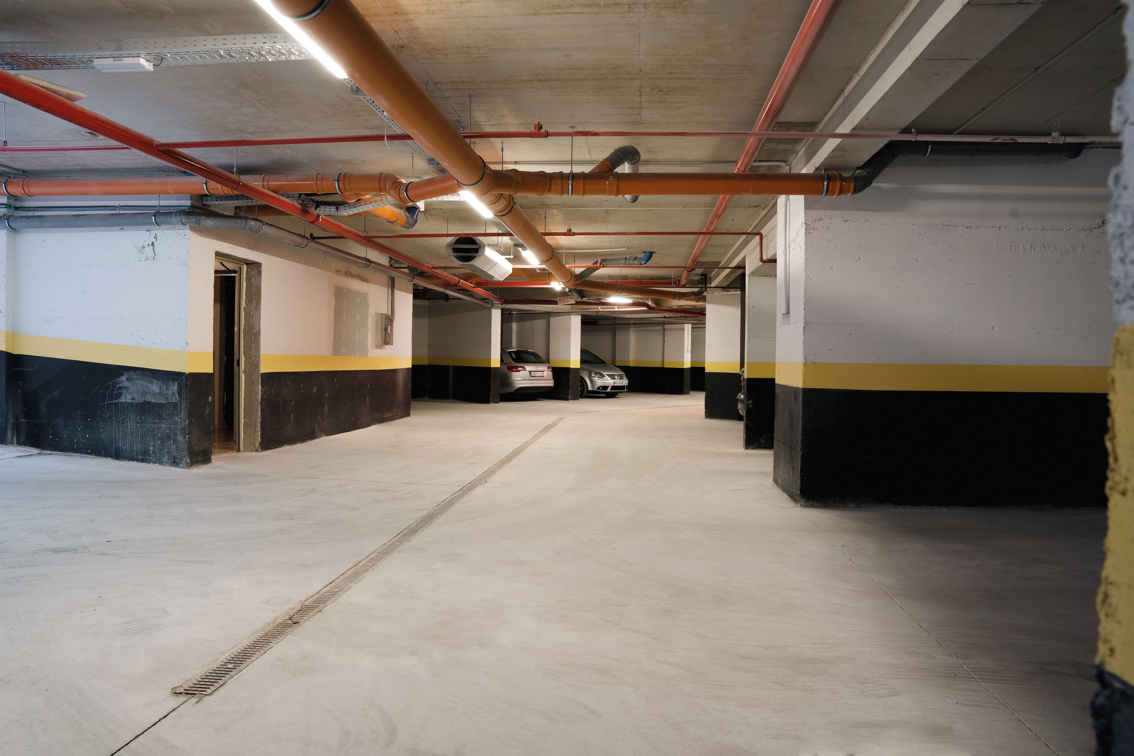 A multi-level parking garage with concrete floors and walls, featuring yellow and black stripes.
