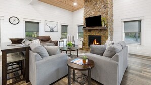 A cozy living room with a stone fireplace, comfortable seating, and a television. - Rustic Hillside Hideaway-2 BR+Bunk-Timber Creek (Broken Bow)