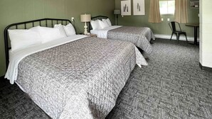 Een hotelkamer met twee bedden, een bureau, een stoel en een raam met gordijnen.