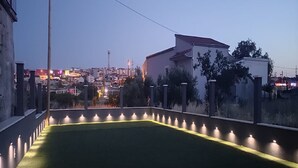 Una azotea con césped y un muro bajo con luces.