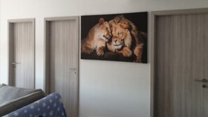 Un dormitorio con una cama, un cuadro colgado en la pared con un león y una puerta.