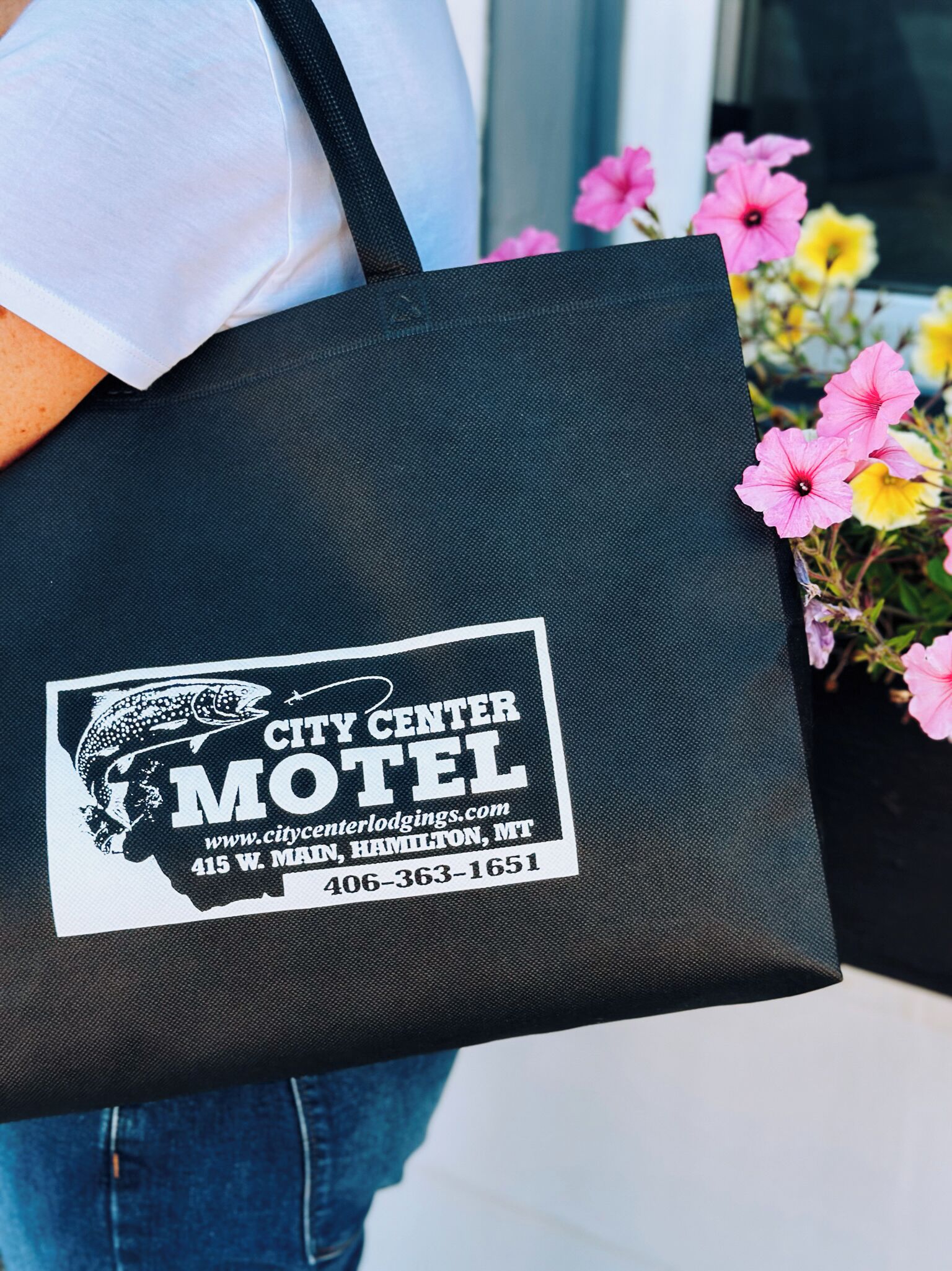 Un sac fourre-tout noir orné du logo du « City Center Motel », avec une représentation d’un poisson et la silhouette d’une montagne.