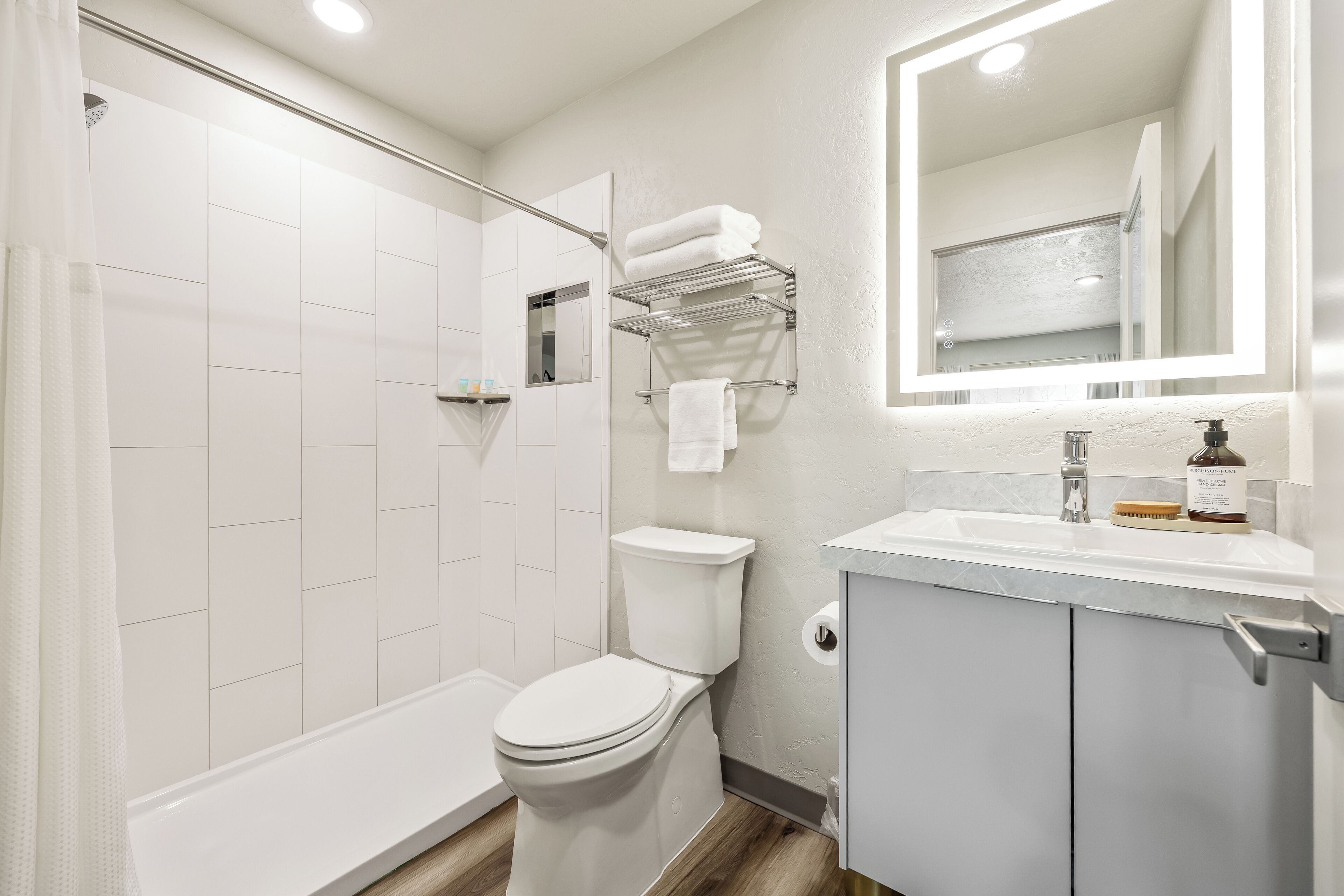 A modern bathroom with a toilet, shower, and sink area.