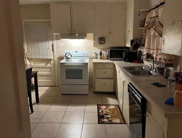 Kitchen features a stove, microwave, and sink, with standard cabinetry and a tiled floor.
