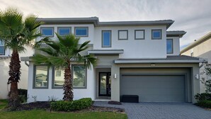 A modern two-story house with a garage, palm trees, and a well-maintained lawn. - Lovely Villa at Kissimmee (Kissimmee)