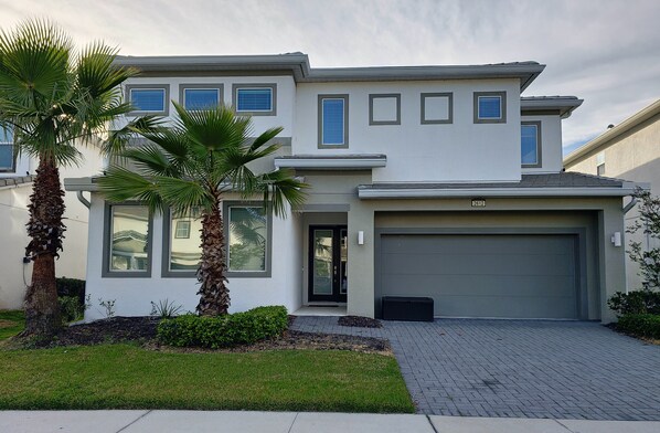 A modern two-story house with a garage, palm trees, and a well-maintained lawn. - Lovely Villa at Kissimmee (Kissimmee)