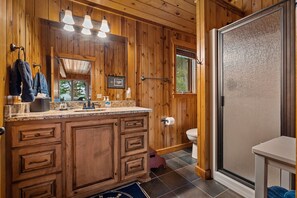 Een houten badkamer in een chalet met een grote wastafel, toilet en een douchehoek.