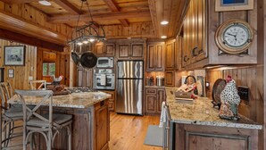 A spacious kitchen with wooden cabinets, stainless steel appliances, and a granite countertop.