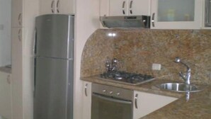 Uma cozinha equipada com geladeira de aço inoxidável, micro-ondas, fogão e pia.