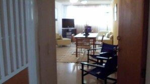 A hallway leading to a living area with a TV, a dining table, and chairs.