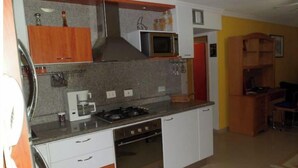 A compact kitchen with a gas stove, microwave, and a coffee maker.
