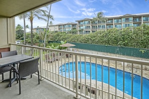 Enjoy a refreshing view of the pool from this balcony with a table and chairs.