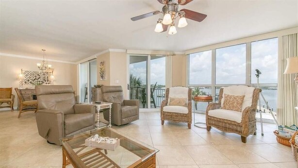 Un salón amplio con una mesa de centro de vidrio, sofás de cuero, sillones de mimbre y un gran ventanal con vistas al exterior.
