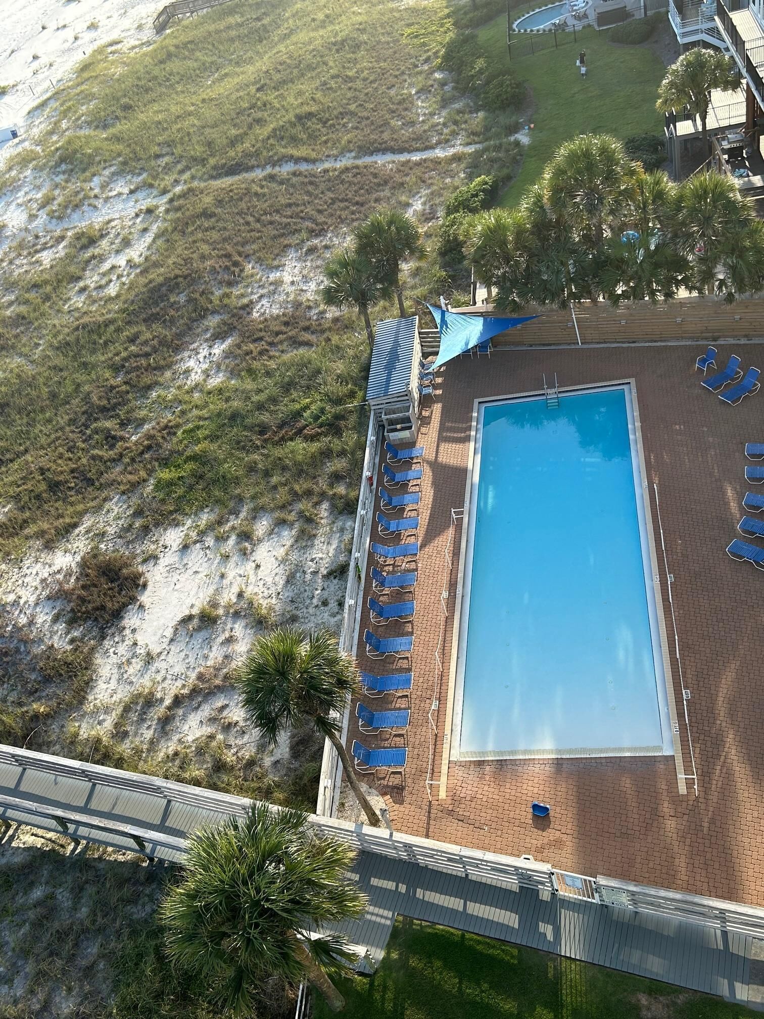 An aerial view of a resort with a swimming pool, lounge chairs, and a deck area.