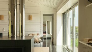 A modern kitchen with stainless steel appliances, a dining area with wicker chairs, and a large window providing a view. - Casas da Prainha   A (Prainha de Baixo)