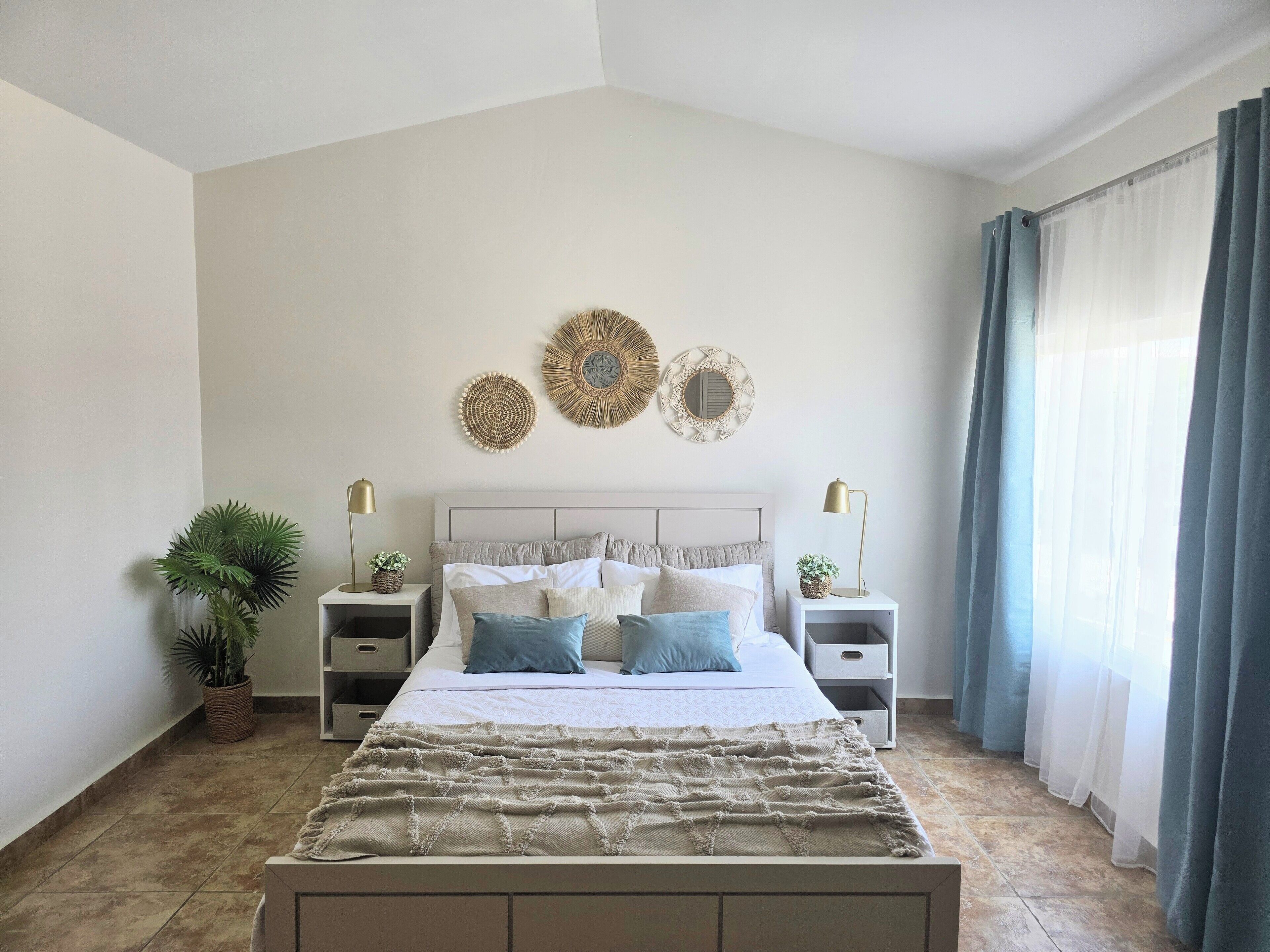 Una camera da letto con un letto, due comodini, una pianta in vaso e decorazioni a parete.