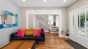 Un amplio espacio de estar con un sofá azul oscuro, una mesa de centro de madera y una escalera que lleva a otro nivel.