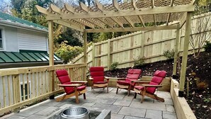 Un patio exterior con terraza de madera, baldosas de piedra y sillas rojas.