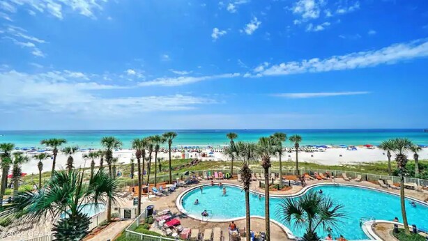 Un resort con una piscina grande, playa y vista al océano.