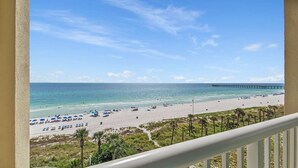 Vista a la playa desde un balcón, con un muelle a lo lejos.
