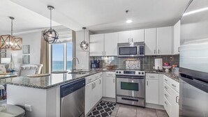 Una cocina moderna con armarios blancos, electrodomésticos de acero inoxidable, lavavajillas y una isla grande con pileta.