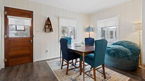 A dining area with a wooden table and chairs, a blue bean bag, and a rug.