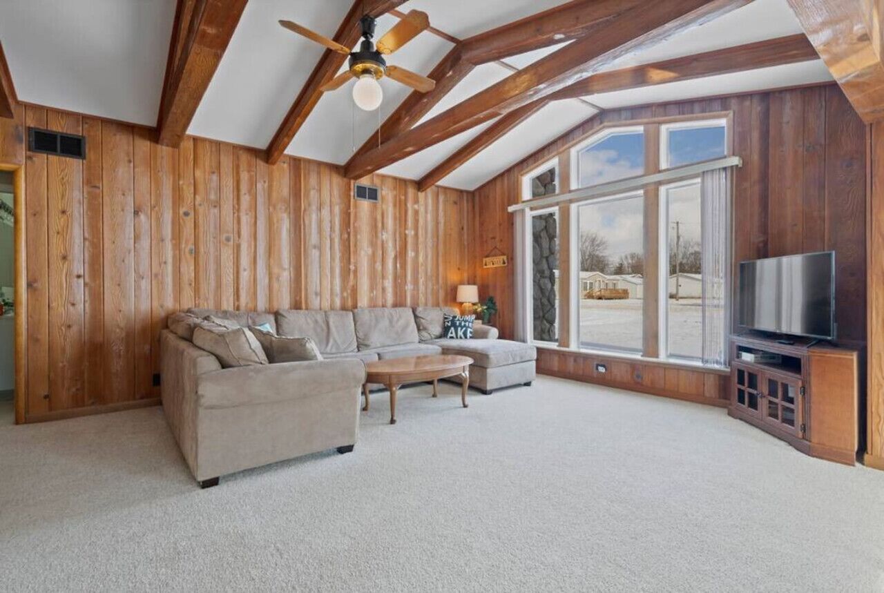 Un salon spacieux avec un grand canapé d’angle, une table basse et un téléviseur posé sur un meuble en bois.