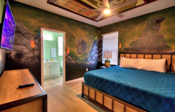 A bedroom with a bed, a nightstand, a TV, and a door leading to a bathroom. - Hacienda Miranda Resort  (Davenport)