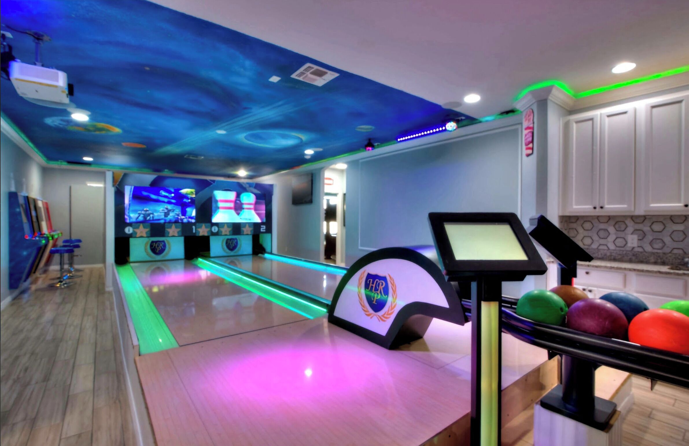 A bowling alley with a modern design, including a digital scoreboard and colorful bowling balls.