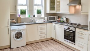 A modern kitchen with a washing machine, microwave, oven, and a sink. - 3 bedroom accommodation in Alnwick (Alnwick)