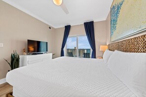 Une chambre d’hôtel avec un grand lit, un téléviseur à écran plat, un bureau et une fenêtre avec des rideaux.