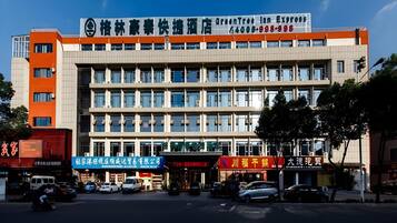 Un hotel de varios pisos con una fachada moderna, que presenta un letrero destacado con caracteres chinos y un número de contacto.