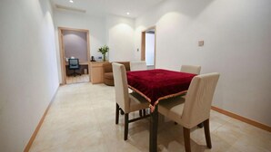 A dining area with a table and four chairs, a small kitchenette in the background, and a door leading to another room. - Greentree Inn Jiangsu Zhangjiagang Jingang Town Darunfa Express Hotel (Suzhou)