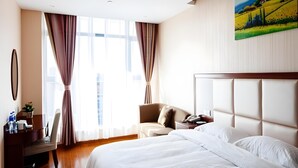 A hotel room with a large bed, a desk, a chair, and a painting on the wall. - Greentree Inn Jiangsu Zhangjiagang Jingang Town Darunfa Express Hotel (Suzhou)
