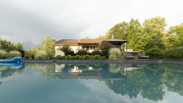 Una casa con piscina, rodeada de vegetación y árboles.