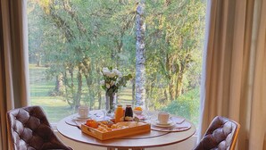 A dining table with two chairs, a tray of food, and a vase of flowers.